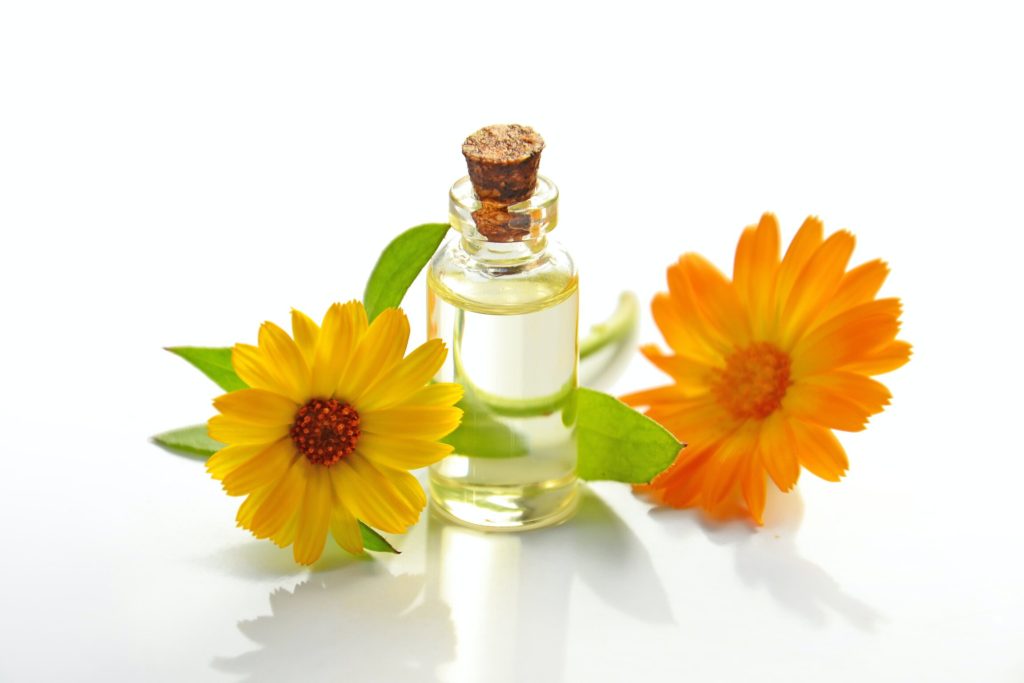 Glass jar containing a flower essence, next to orange and yellow flowers. Is herbal medicine clinically proven? How we know it can work.