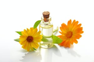 Glass jar containing a flower essence, next to orange and yellow flowers. Is herbal medicine clinically proven? How we know it can work.