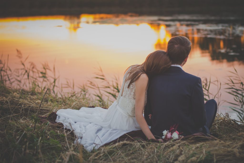 Couple sitting by a pond at sunset. Learning to hope again. Rediscovering yourself after trauma.