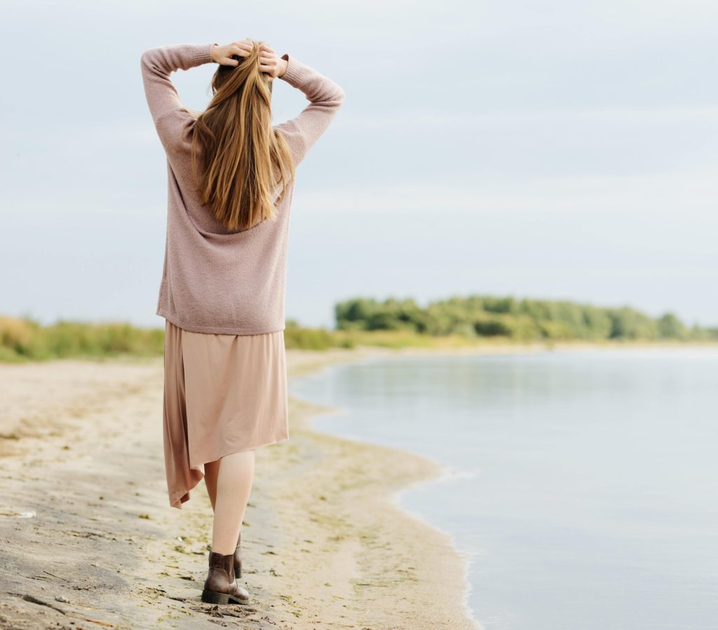 Woman walking along the shore of a lake. Re-engaging with life.