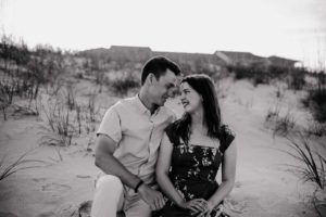 Jonathan and Hannah sitting together on the sand at the beach. A quick health update for 2023.